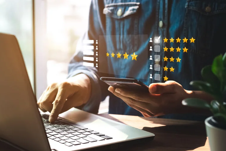An image of an individual at a laptop while on their phone. An overlay of metrics and star ratings is in the frame.