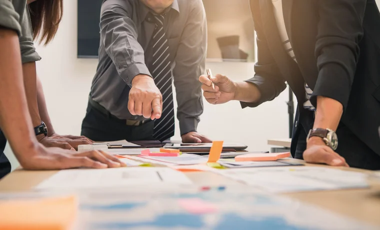 A group of coworkers work together on a communication plan at a work table