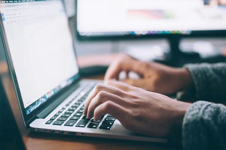 Close up of someone typing on a laptop
