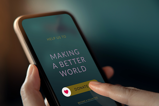 An image of someone on their phone, donating to a charity, text on the phone reads "Make The World Better"