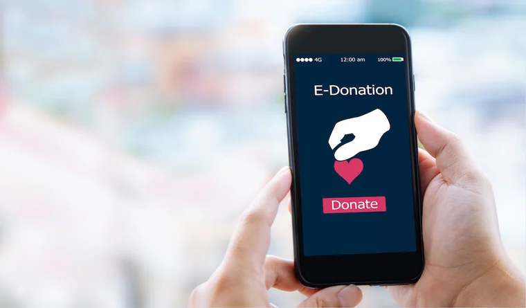 An individual holds a phone in hand, getting ready to donate to a mobile giving campaign