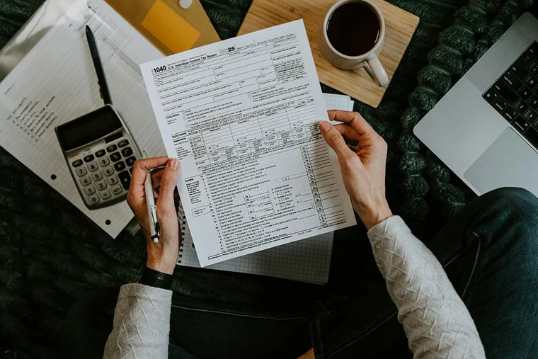 An individual sits at a desk with his tax form in hand