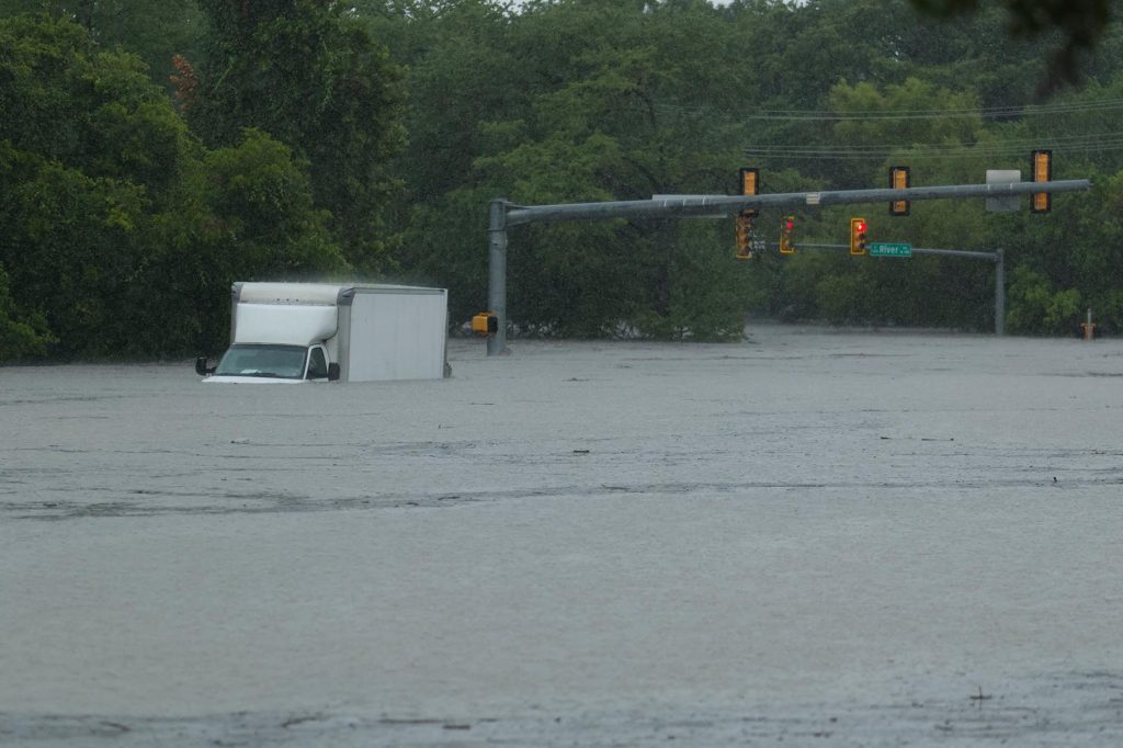 A truck sits submerged in flood waters at an intersection on Wednesday, July 15, 2026, in Boerne, Texas. (AP Photo/Darren Abate)