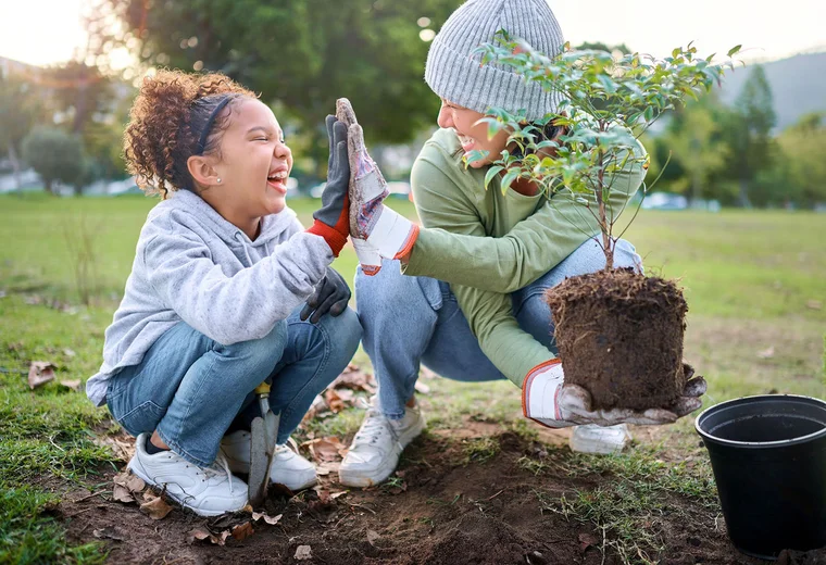 Mother and child high-fiving while planting a tree