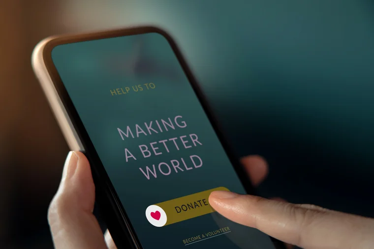 Someone holds a phone in their hand, donating to a charity on their mobile website