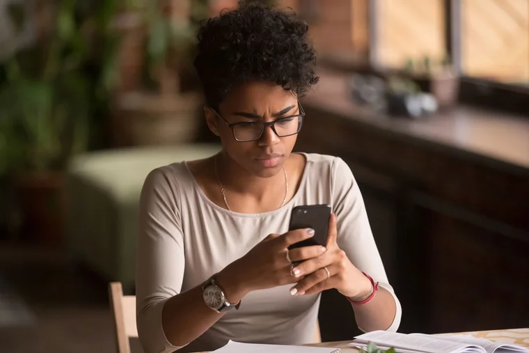 A women looks at her phone confused