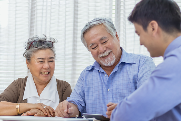 A couple smiling while going over paperwork with an advisor