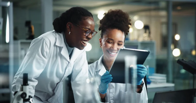 Two Black female scientists looking at a tablet in a laboratory