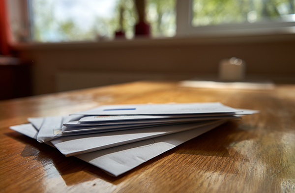 A stack of mail siting on a kitchen table