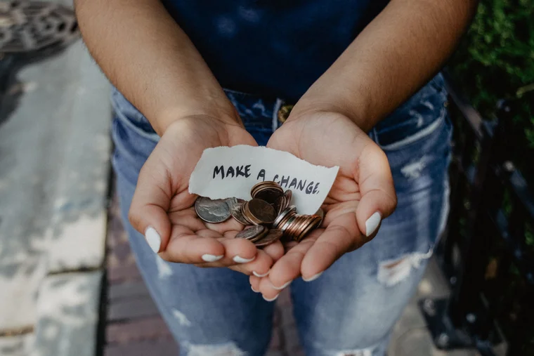 Close up of someone holding change and a paper that says "Make a Change"