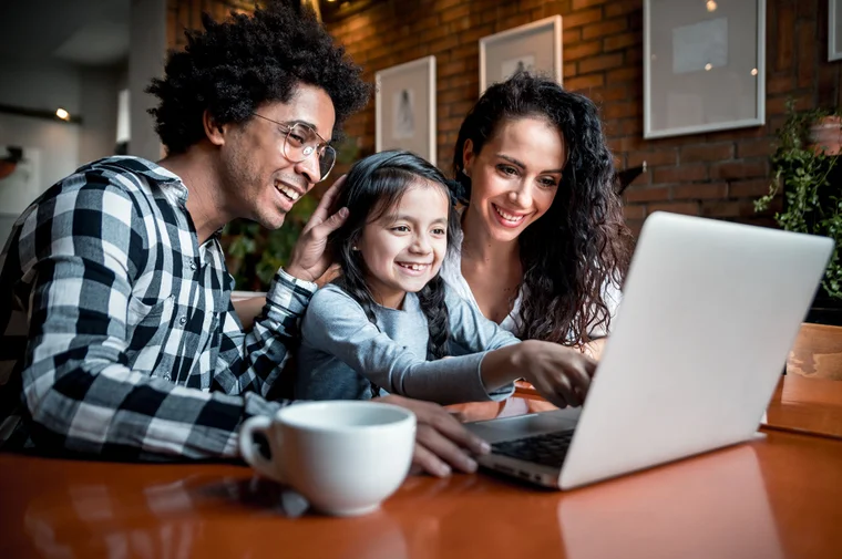 A smiling family looking at their laptop