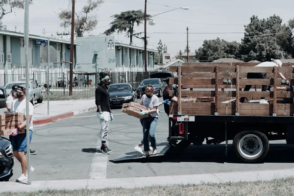 A group of volunteers carry palettes of donations from a truck