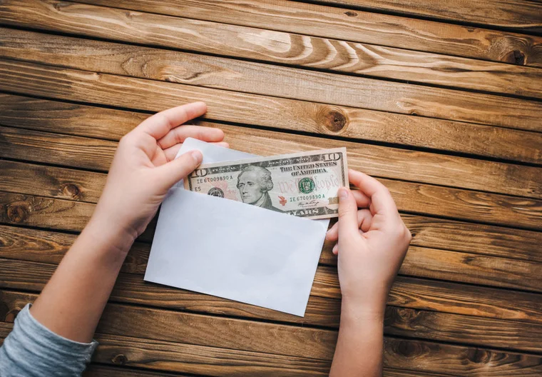 Hand pulling money from an open envelope
