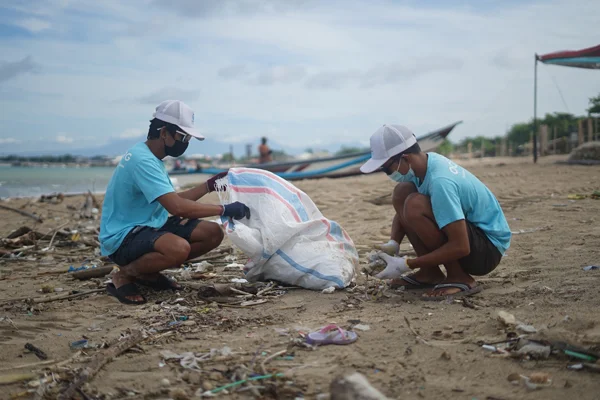 Two volunteers clean up litter on a beach